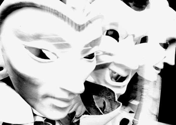 "Maschere Veneziane" è il titolo di questa fotografia in bianco e nero. La foto mostra appunto tre maschere Veneziane con diversi espressioni. La foto trasmette una certa dinamica in quanto leggermente sfogata con segni di movimento che fanno sembrare le maschere quasi viventi e un po' inquietanti.