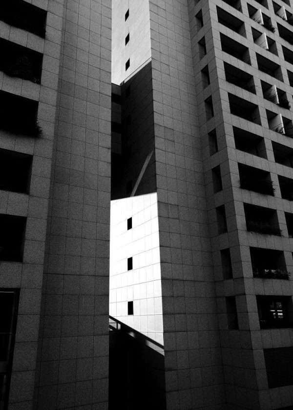 l'Eurosky Tower a Eur Torrino a Roma è l'edificio più alto di Roma e il palazzo residenziale più alto d'Italia. Questa inquadratura in bianco e nero cattura il gioco della luce del sole e l'ombra dello stesso edificio. Una fotografia d'architettura urbana contemporanea con contrasti forti e lineari.