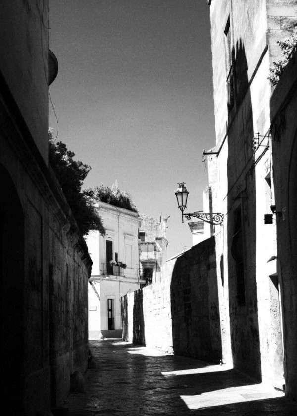 Una via nel centro storico di Lecce in Puglia, Italia. Il sole forma ombre simmetriche e incisive che sono l'essenza di questa fotografia in bianco e nero.